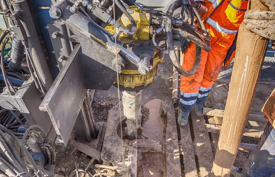Técnico con equipo de protección ejecutando un sondeo geotécnico en obra